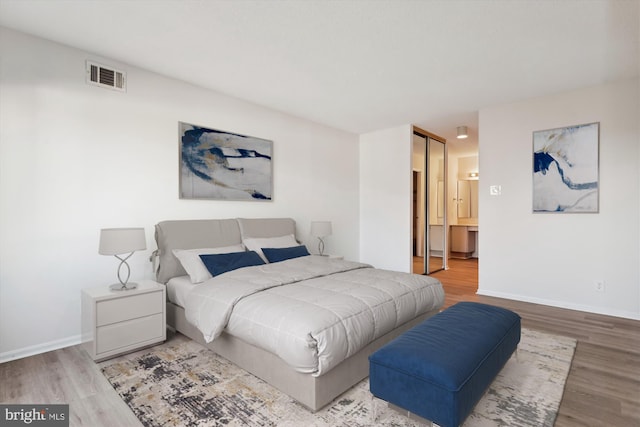 bedroom featuring hardwood / wood-style floors, ensuite bathroom, and a closet