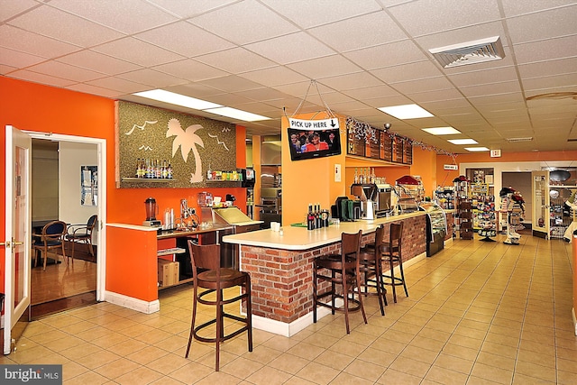 bar featuring light tile patterned floors and a drop ceiling