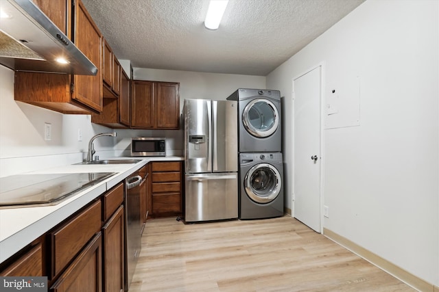 washroom with stacked washer and dryer, light hardwood / wood-style floors, a textured ceiling, and sink