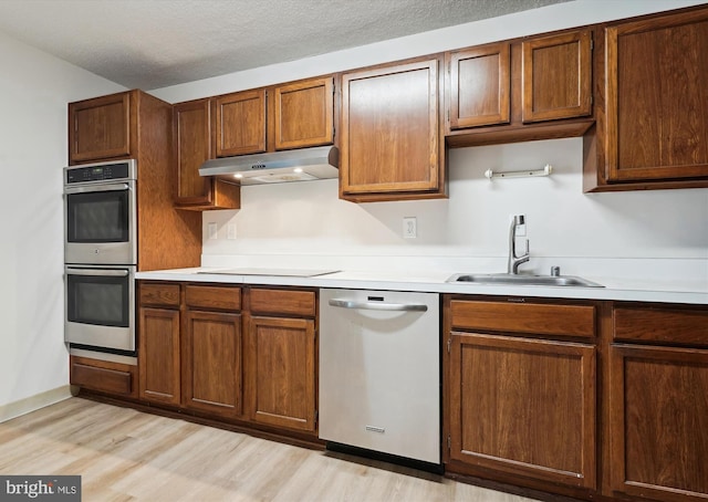 kitchen with sink, light wood-type flooring, a textured ceiling, and appliances with stainless steel finishes