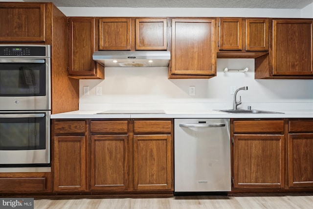 kitchen with light hardwood / wood-style flooring, stainless steel appliances, a textured ceiling, and sink