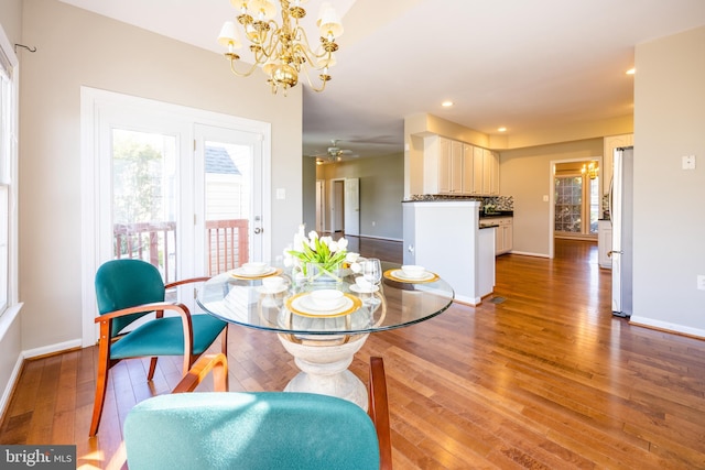 dining area featuring ceiling fan with notable chandelier and dark hardwood / wood-style floors