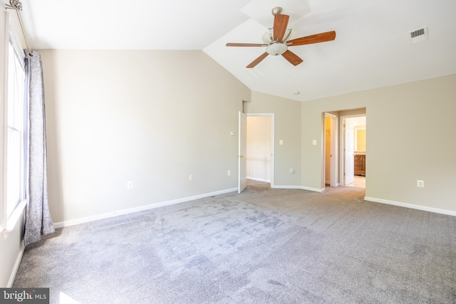 carpeted empty room with ceiling fan, plenty of natural light, and vaulted ceiling