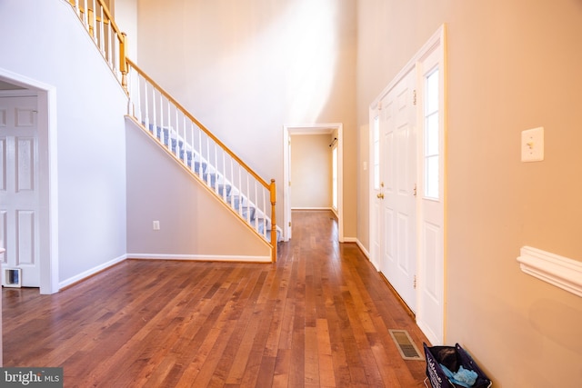 entryway with dark wood-type flooring and a high ceiling