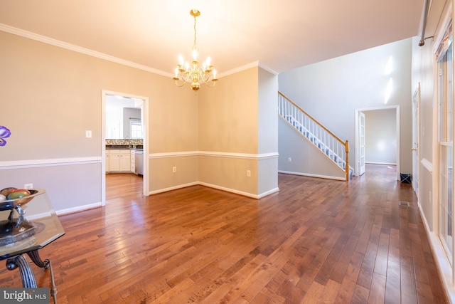 spare room featuring a chandelier, crown molding, and hardwood / wood-style flooring