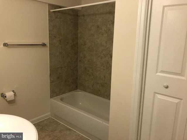 bathroom with tile patterned flooring, toilet, and tiled shower / bath combo