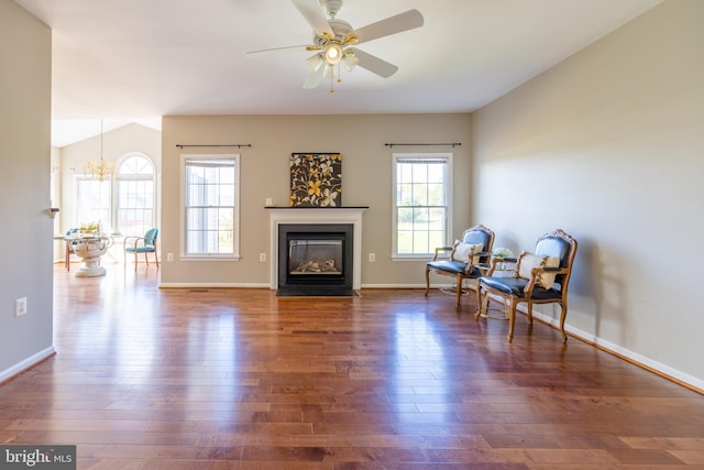 living area with ceiling fan with notable chandelier and dark wood-type flooring