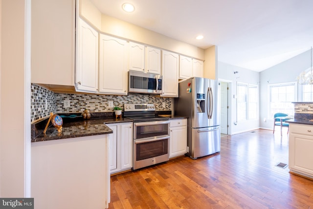 kitchen featuring white cabinets, stainless steel appliances, lofted ceiling, and light hardwood / wood-style flooring