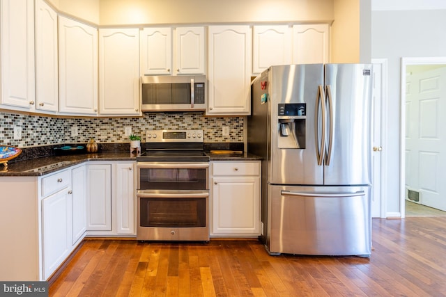 kitchen with stainless steel appliances, dark hardwood / wood-style floors, white cabinets, and backsplash