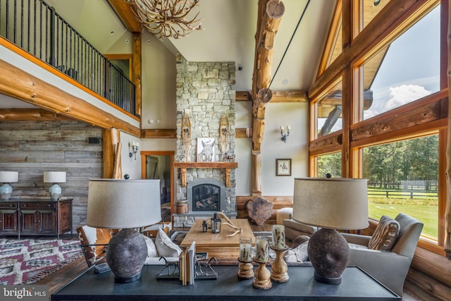 interior space featuring wood-type flooring, high vaulted ceiling, beam ceiling, and a stone fireplace