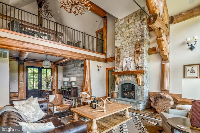 living room with high vaulted ceiling, beamed ceiling, a stone fireplace, french doors, and hardwood / wood-style flooring