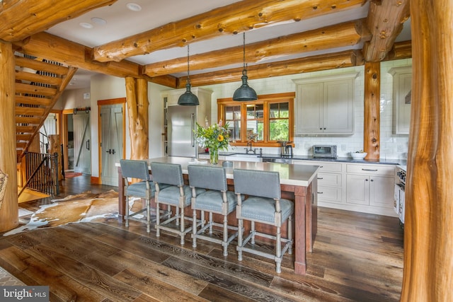 kitchen with a center island, dark hardwood / wood-style floors, hanging light fixtures, beam ceiling, and backsplash