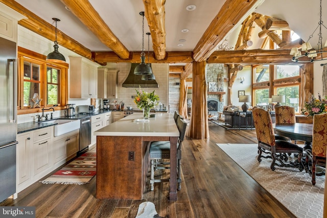 kitchen with hanging light fixtures, beam ceiling, and plenty of natural light