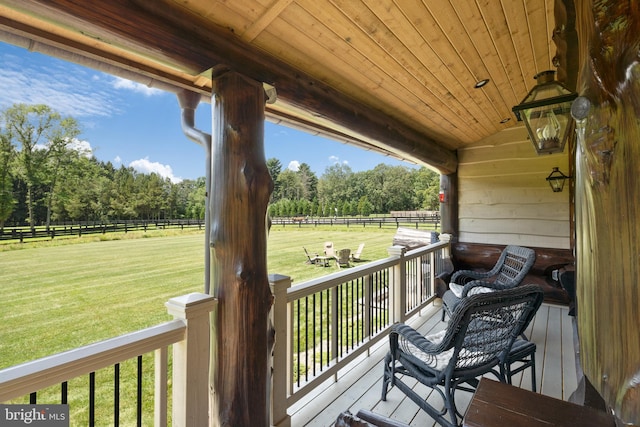 deck featuring a porch, a rural view, and a lawn