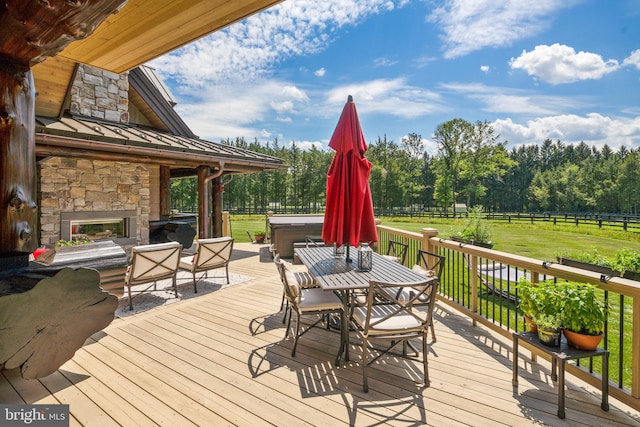 wooden terrace featuring an outdoor stone fireplace and a rural view