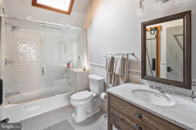 full bathroom featuring tile patterned flooring, enclosed tub / shower combo, toilet, tile walls, and vanity