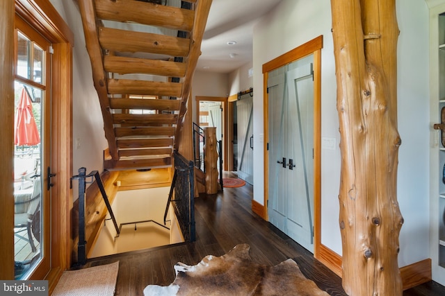 interior space with a barn door and dark hardwood / wood-style floors