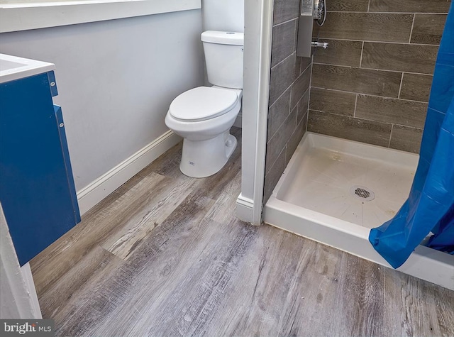 bathroom with walk in shower, hardwood / wood-style flooring, vanity, and toilet