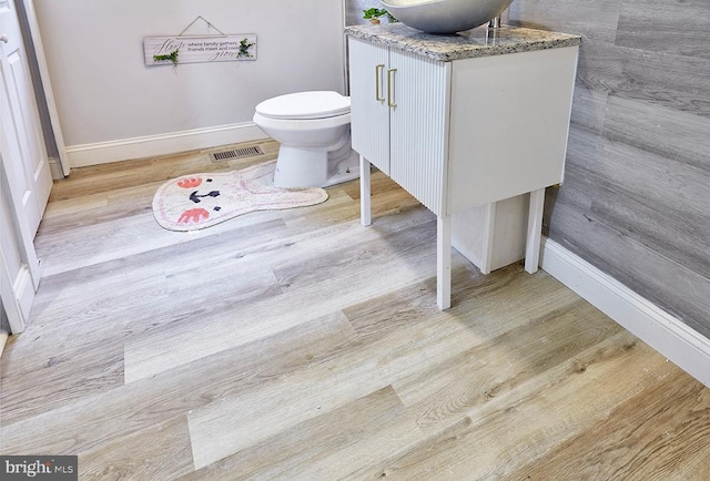 bathroom with hardwood / wood-style floors, vanity, and toilet