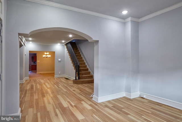 spare room with a chandelier, crown molding, and light hardwood / wood-style flooring