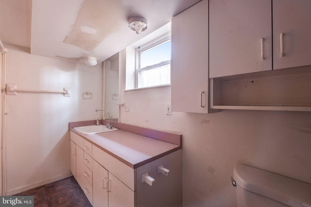 bathroom featuring parquet flooring, vanity, and toilet