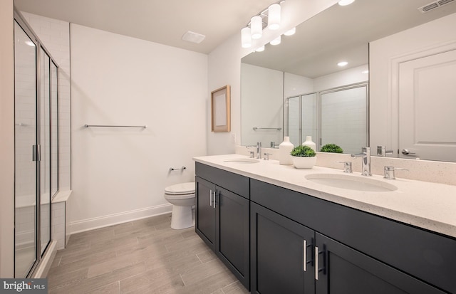 bathroom with hardwood / wood-style floors, vanity, walk in shower, and toilet