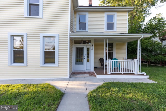 entrance to property featuring a yard and covered porch