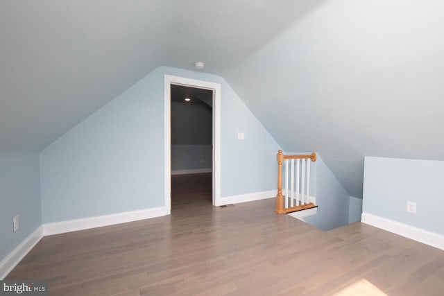 additional living space featuring lofted ceiling and dark wood-type flooring