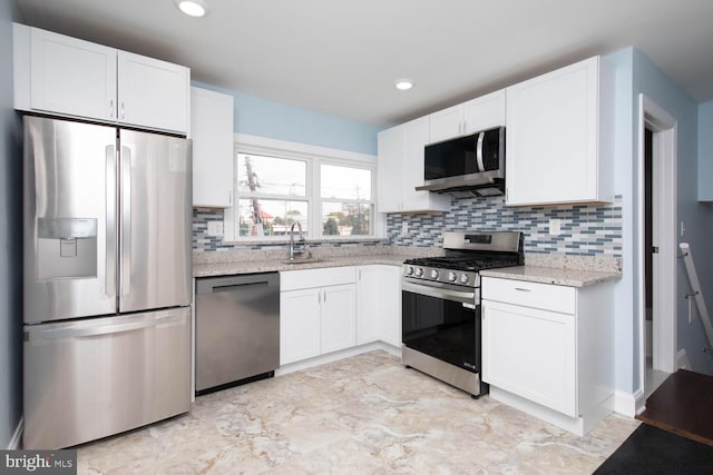 kitchen with light stone countertops, appliances with stainless steel finishes, tasteful backsplash, and white cabinetry