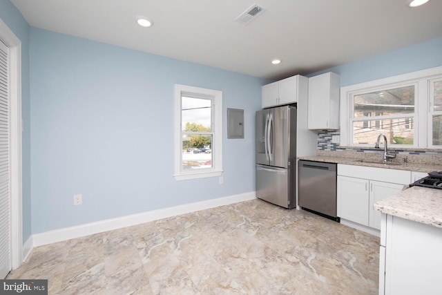 kitchen with white cabinets, sink, stainless steel appliances, light stone countertops, and decorative backsplash