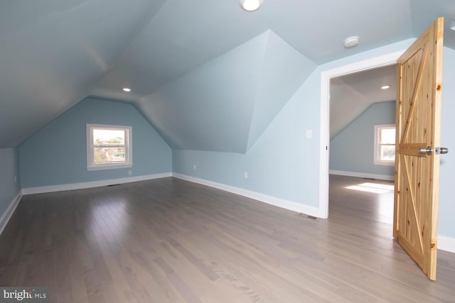 bonus room with wood-type flooring, lofted ceiling, and a healthy amount of sunlight