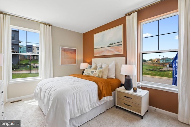 bedroom with multiple windows, visible vents, baseboards, and light colored carpet