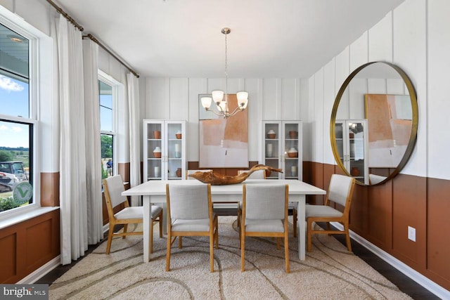 dining area featuring a decorative wall, a chandelier, and wood finished floors
