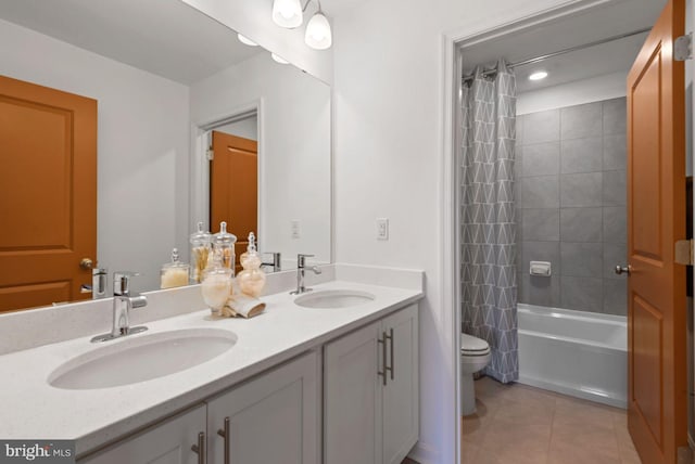 bathroom with toilet, tile patterned floors, double vanity, and a sink
