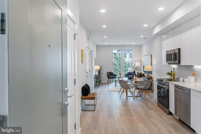 kitchen with appliances with stainless steel finishes, light hardwood / wood-style floors, and white cabinets