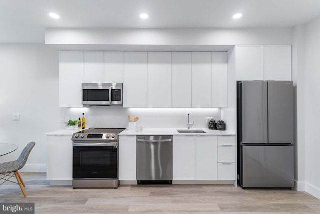 kitchen featuring white cabinets, stainless steel appliances, sink, and light wood-type flooring