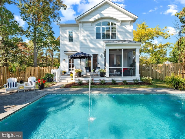 back of property with a sunroom, a fenced in pool, and a patio