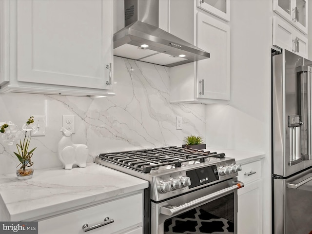 kitchen featuring wall chimney exhaust hood, tasteful backsplash, high quality appliances, light stone counters, and white cabinets