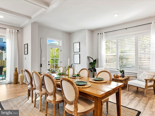 dining area featuring beamed ceiling, light wood-type flooring, and a healthy amount of sunlight