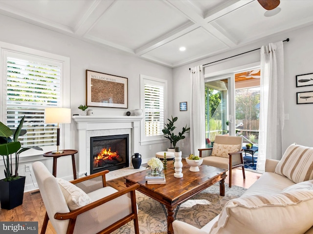 living room with a high end fireplace, coffered ceiling, hardwood / wood-style flooring, and a wealth of natural light