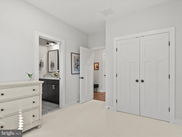 carpeted bedroom featuring a closet and ensuite bathroom