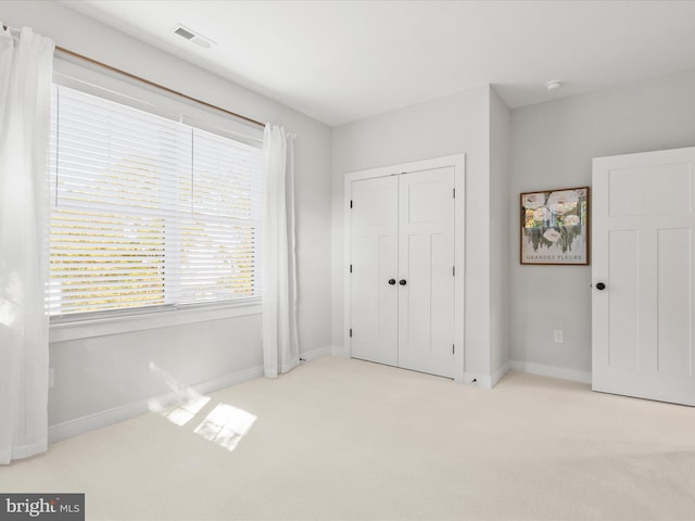 unfurnished bedroom with light carpet and a closet