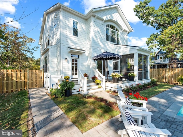 view of front of property featuring a sunroom and a patio