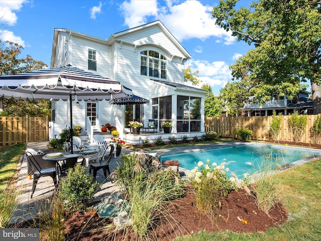 rear view of house with a fenced in pool, a sunroom, and a patio area