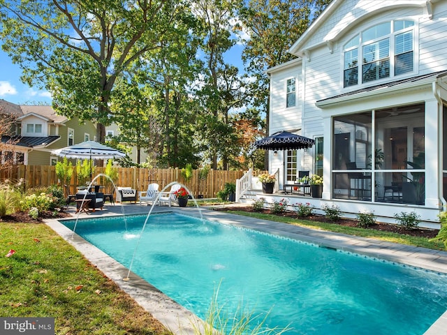 view of pool with a sunroom, pool water feature, and a patio area