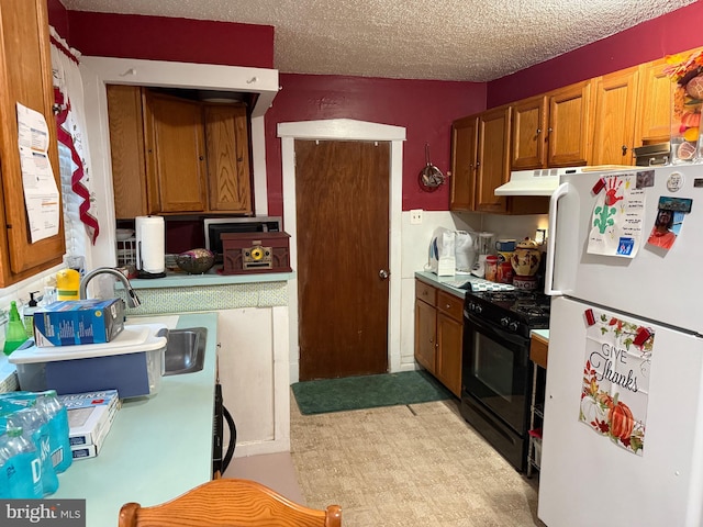 kitchen featuring black range with gas stovetop, white refrigerator, and a textured ceiling