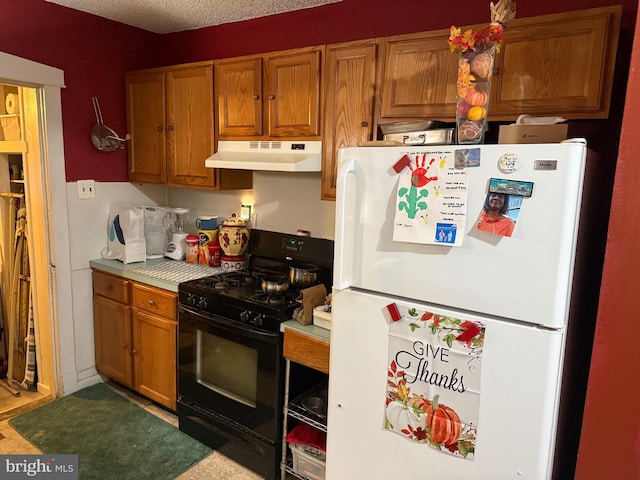 kitchen with a textured ceiling, white fridge, and gas stove