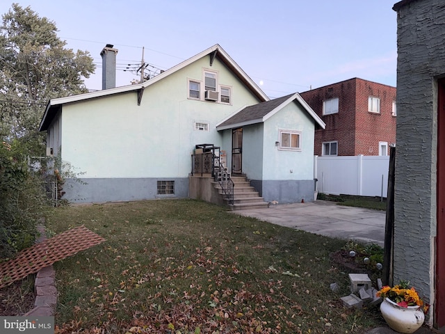 rear view of property with cooling unit and a yard