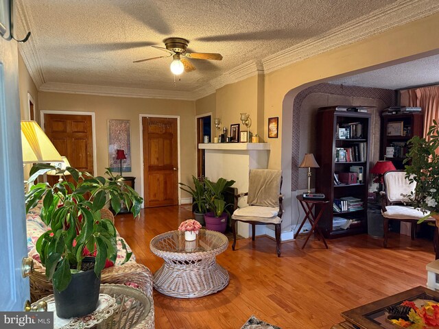 living area with crown molding, hardwood / wood-style floors, and a textured ceiling