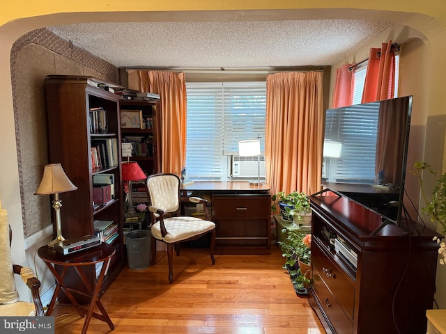 living area featuring cooling unit, light hardwood / wood-style flooring, and a textured ceiling